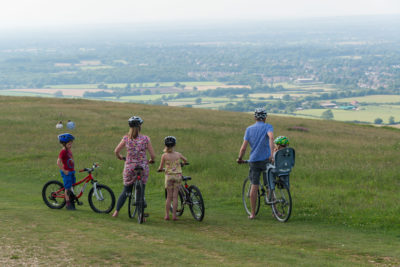 Family cycling during the day at Ditchling Beacon overlooking the South Downs.