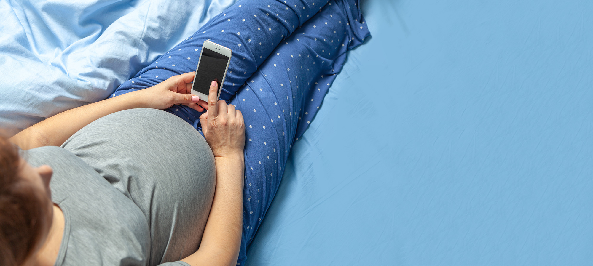 Pregnant woman with belly holds smartphone in hands. Copy space for text