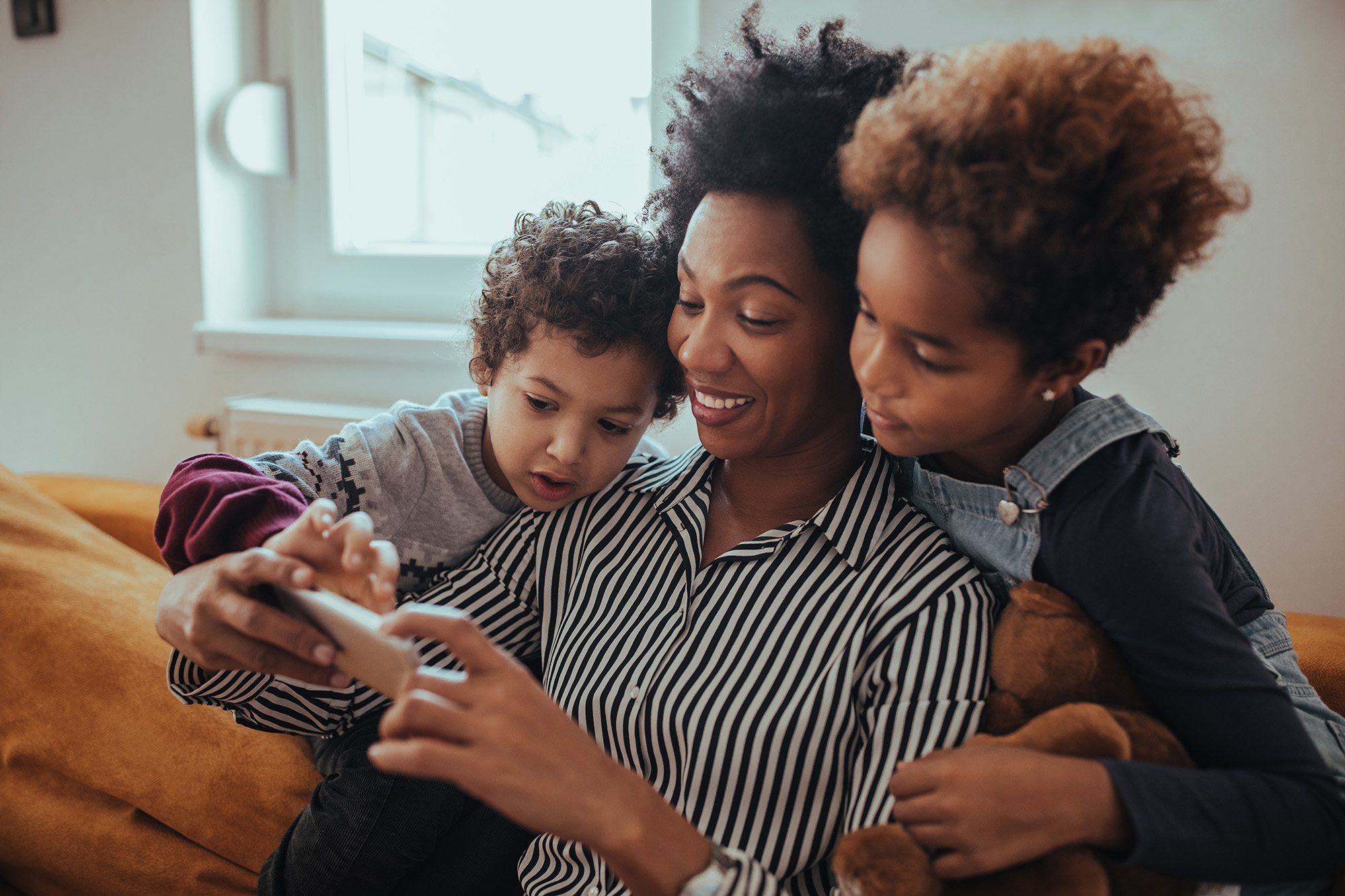 Shot of a mother looking at something on the mobile phone with her children