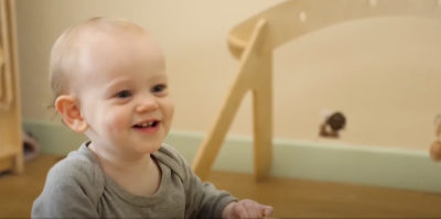 Image from Acorn childcare video of a smiling baby playing