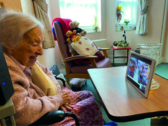 Irene Baker enjoying a virtual tour using an iPad, sat in her care home