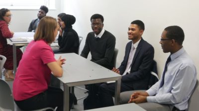 A group of Year 12 students in a classroom having a discussion around a table