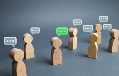Wooden figures representing people with speech bubbles, representing them talking