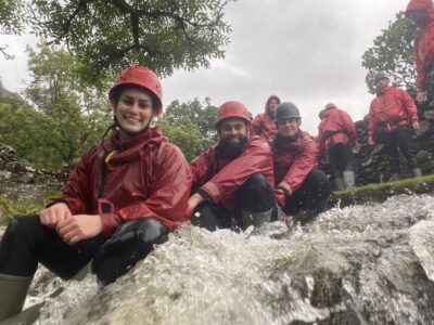 A photo of Amelia and several people behind her, wearing helmets and sitting by a stream, smiling