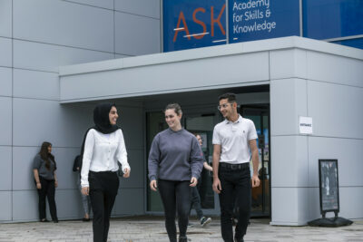 A picture of Ammaarah on the left-hand side, walking alongside to people, outside a college