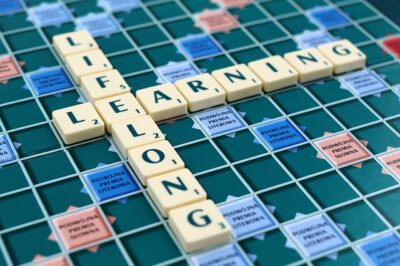 A scrabble board with the words "learning and lifelong" on the board