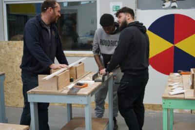 A photo of two young people learning construction skills from an instructor